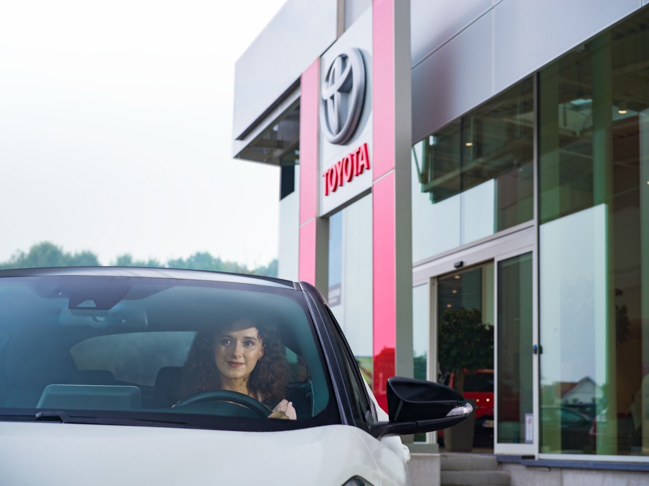 Woman driving away from Toyota Dealership
